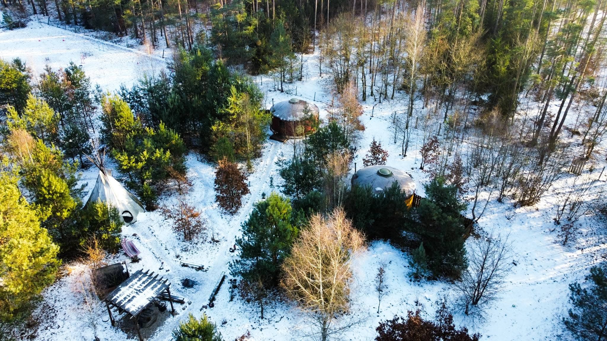 Zaśnieżone siedlisko z lotu ptaka, jurty i sauna wśród ośnieżonych drzew